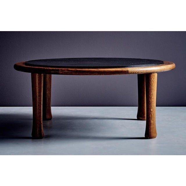 Oval oak coffee table with an inset slate top. A thick rounded oak rim surrounds the dark slate surface, and the table...