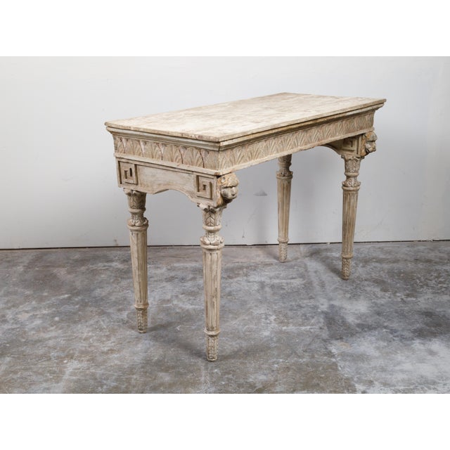 An Italian Neoclassical console table from the 18th century, with carved animals, fluted legs and distressed patina....