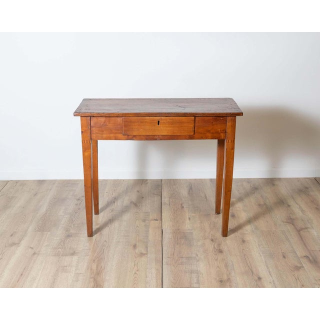 A charming late 18th century Tuscan side table crafted in solid walnut, displaying the understated elegance and...
