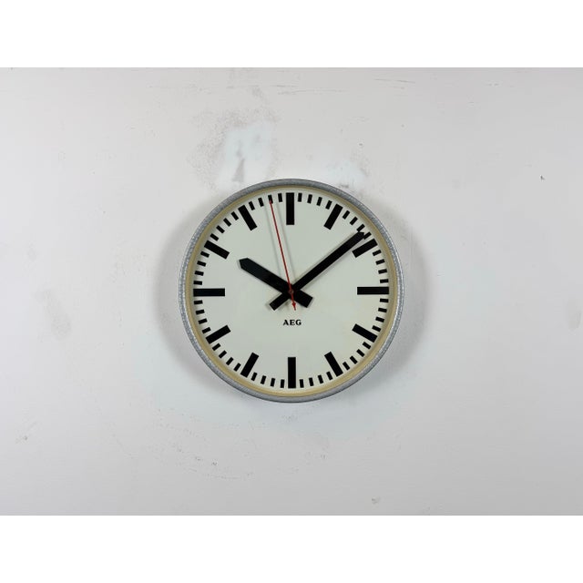 This wall clock was produced by AEG in Germany during the 1960s. It features a grey hammerpaint iron frame, a metal dial...