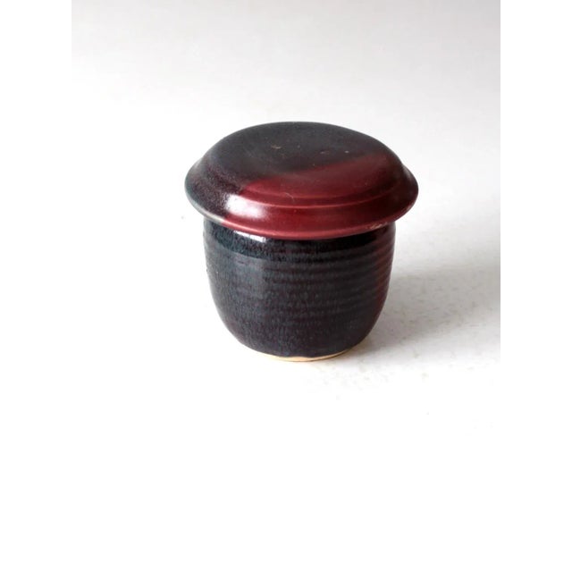 This is a vintage studio pottery jar. Signed by the artist, the handmade jar features a charcoal and raspberry glaze. Its...