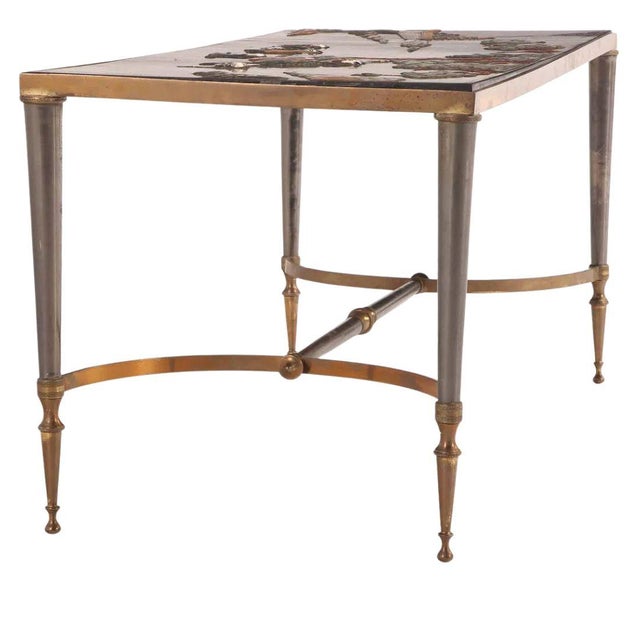A Jansen style carved and painted chinoiserie coffee table with a wood top and brass and steel base. The vintage table top...