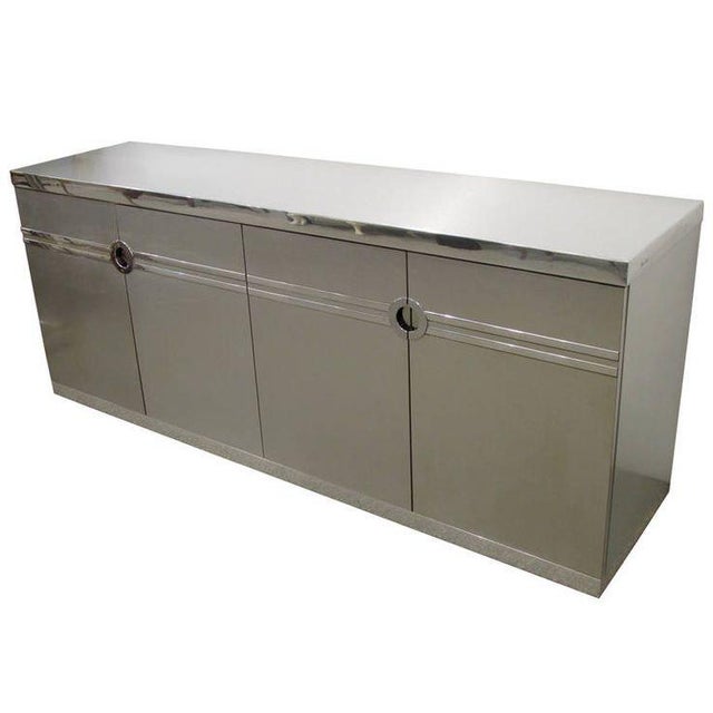 A vintage Pierre Cardin buffet/Credenza features three cabinet hinged doors and a chrome trim accented top and base....