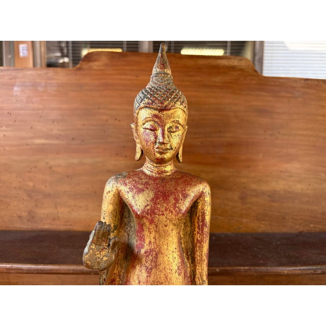This remarkable standing Burmese Buddha is an antique carved wooden sculpture, covered in red lacquer and gold leaf. Its...
