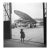 Young Traveller by Toni Frissell A young girl stands in her raincoat awaiting a plane to be refilled for her travels....