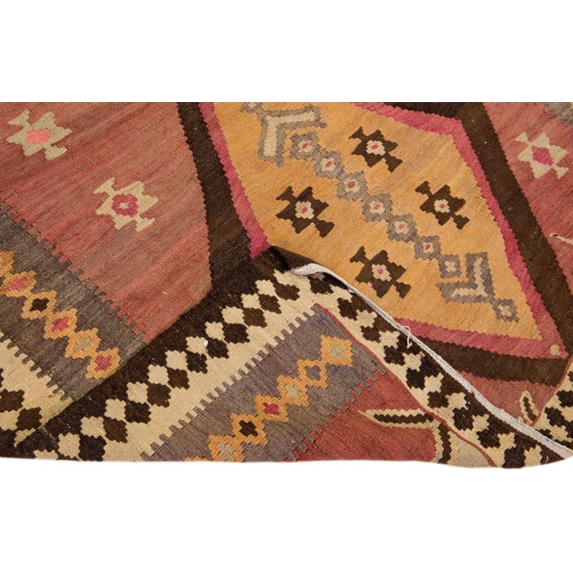 Beautiful vintage Turkish Kilim hand-knotted wool rug with a rust field. This piece has a brown frame and multicolor...