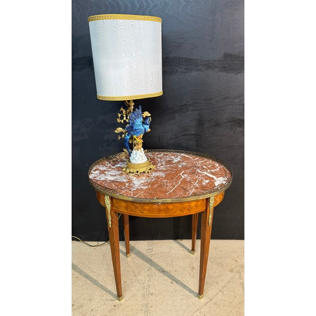 A fine quality French Oval Lamp Table. Having a drawer to the front and 2 slides either side. Adorned with parquetry and...