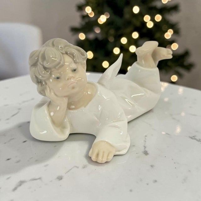 A Lladro Little Angel Reclining porcelain figurine, model #4541, produced in Spain during the late 20th century. Belonging...