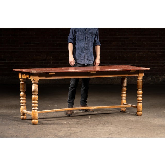 Primitive pine harvest table featuring a long, plank-style top finished in its original worn red paint. The surface shows...
