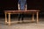Primitive pine harvest table featuring a long, plank-style top finished in its original worn red paint. The surface shows...