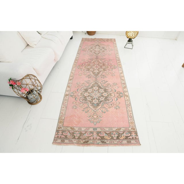 This is a vintage Turkish Oushak rug from the Mid 20th Century. The piece was hand-knotted.