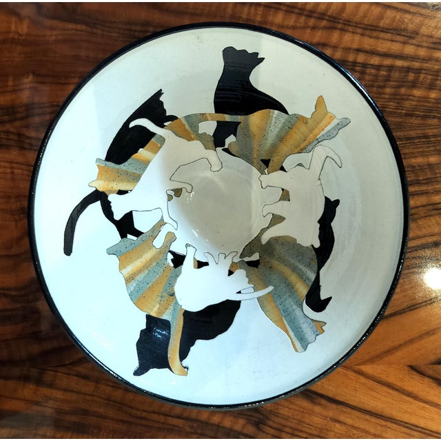 Charming American Studio ceramic bowl with black rim and foot and black, white and striped cat silhouette design inside...