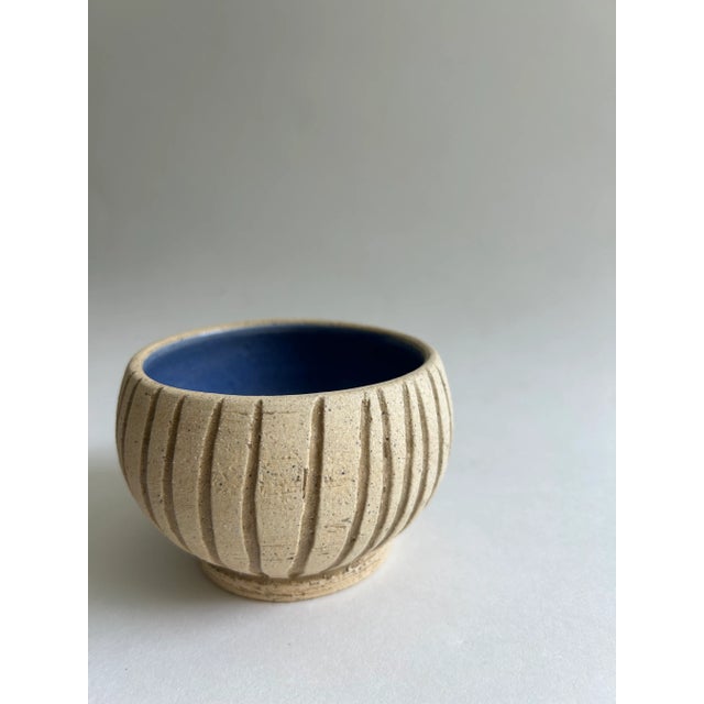 Handmade cream bowl with decorative pattern on exterior and blue glazed interior.