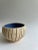 Handmade cream bowl with decorative pattern on exterior and blue glazed interior.