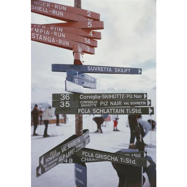 Signpost In St Moritz 1963 by Slim Aarons Slim Aarons Limited Estate Edition A signpost indicating various ski slopes and...