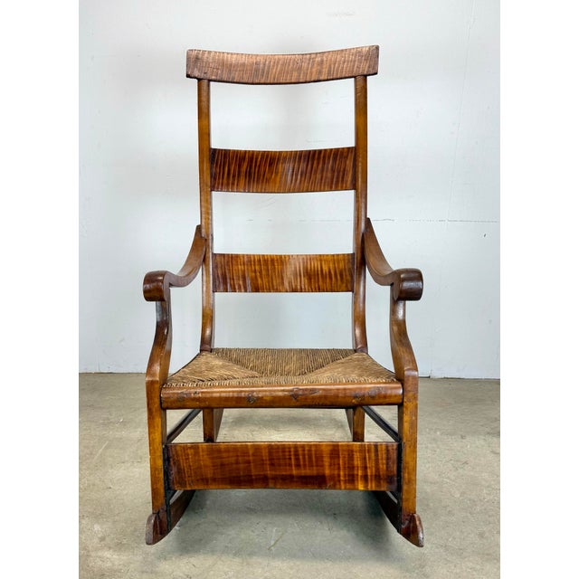 A beauty! A circa 1800’s tiger maple and rush seat ladder back rocking chair showing incredible age and patina. Has had...