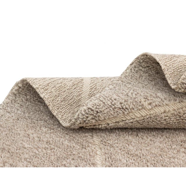 Luxurious hand-knotted wool rug, featuring a neutral Sand hue with a subtle hand-woven Ivory line pattern, designed to...