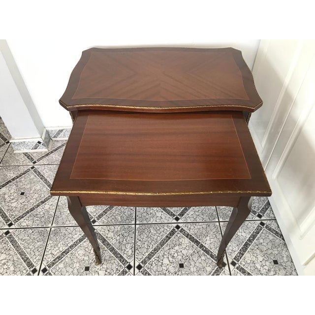 Set of 2 walnut tables with brass applications in the Ludwik style, 1970s. Walnut coffee tables veneered with natural...