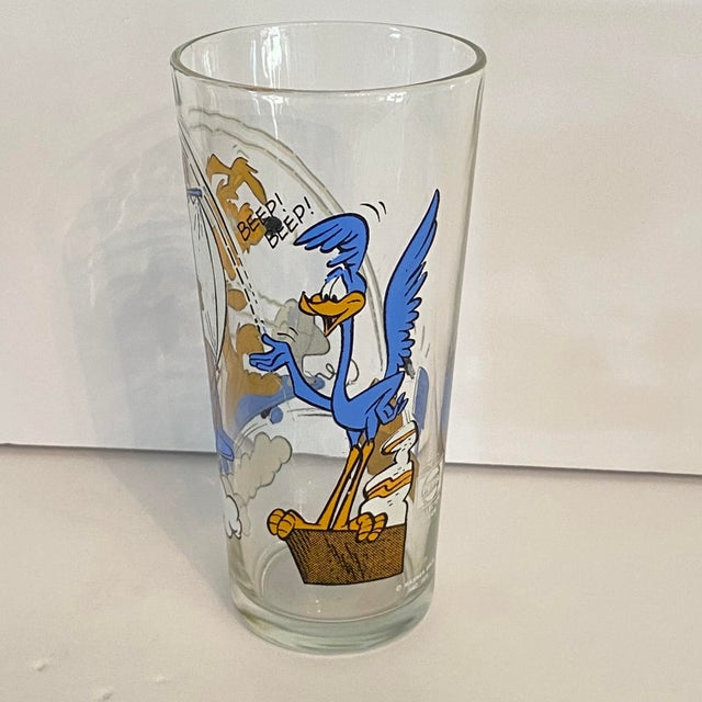 This glass shows Wile E. Coyote desperately operating a makeshift sailplane (or glider) powered by a small electric fan...