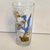 This glass shows Wile E. Coyote desperately operating a makeshift sailplane (or glider) powered by a small electric fan...