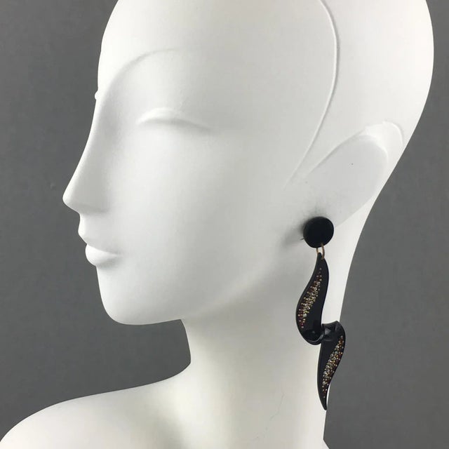 Spectacular long Lucite dangling clip-on earrings. Features a geometric dimensional coiled pattern in shiny black color...