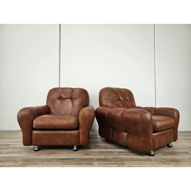 An elegant pair of brown leather armchairs from the 1970s, ideal for any modern or antique vintage setting. Note the...