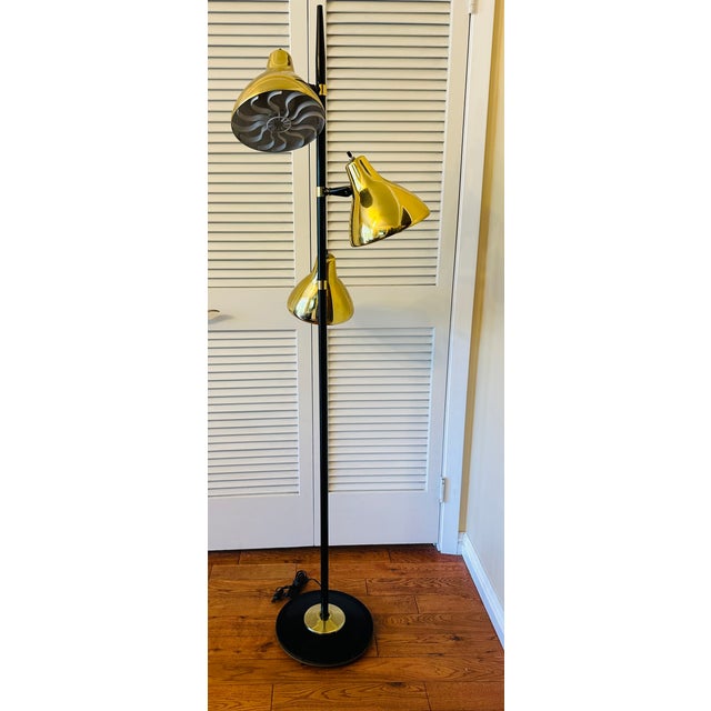 A three headed adjustable pole floor lamp with brass shade, circa 1960s. Rare color combination. The metal pole is in a...