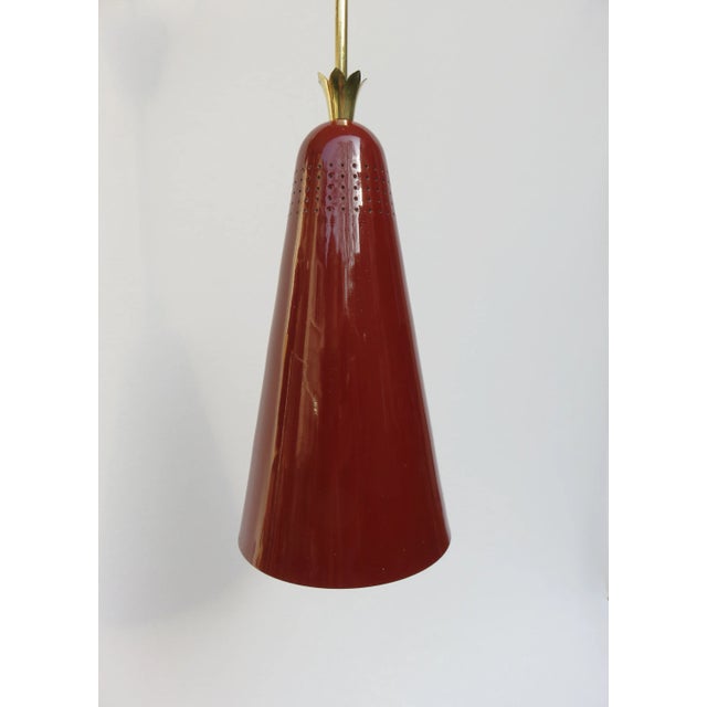 This pendant light from the 1950s was produced in Italy. The lampshade is made of rust-brown lacquered aluminum and has a...