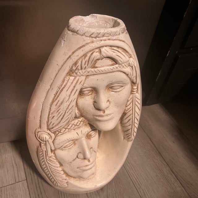 Handcrafted ceramic vase in an off-white color with a matte finish. This piece has two relief-carved Native American faces...