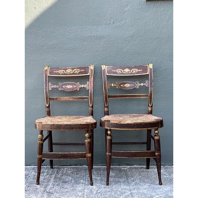 This exquisite pair of antique Hitchcock-style side chairs is a masterwork of 19th-century American craftsmanship....