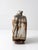 This sculptural mid-century studio pottery vase features a flattened bottle form and an expressive earth-toned glaze....