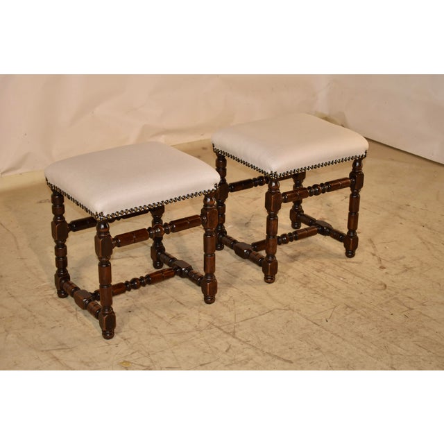 Pair of 19th century turned walnut upholstered stools from France. The seats, newly upholstered in cotton and finished...