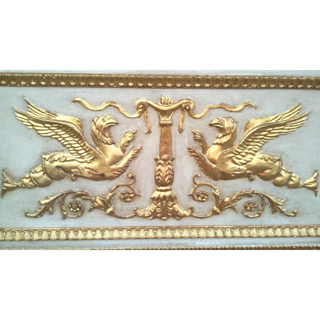 Antiqued ivory-colored trumeau pier mirror with gold leaf finish, accented with a pair of ornately gilded griffins in the...