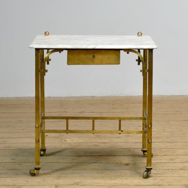 Elegant small brass table with a marble top, dating from circa 1910. This piece of furniture is characterized by a sleek,...