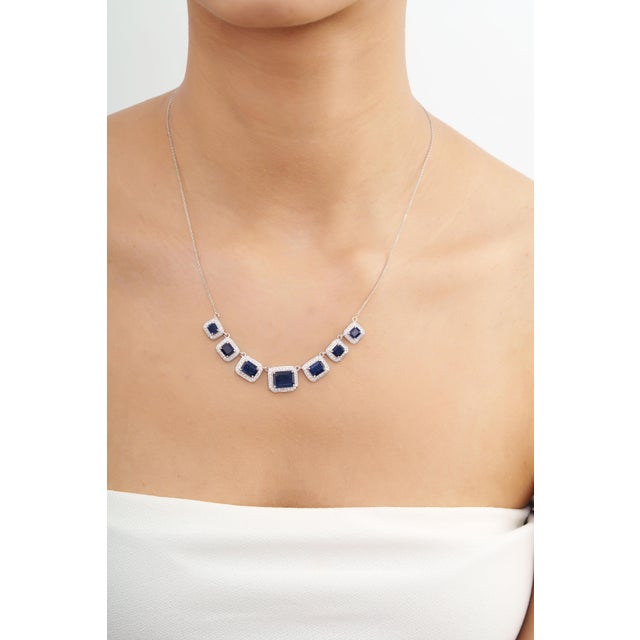 This striking station necklace features 7.3 carats of vibrant natural emerald-cut blue sapphires, set in 14k white gold....