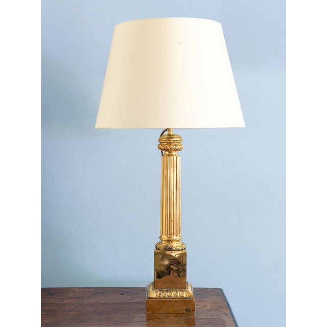A striking French midcentury brass column lamp, featuring a square base adorned with stylised leaves, a fluted shaft with...