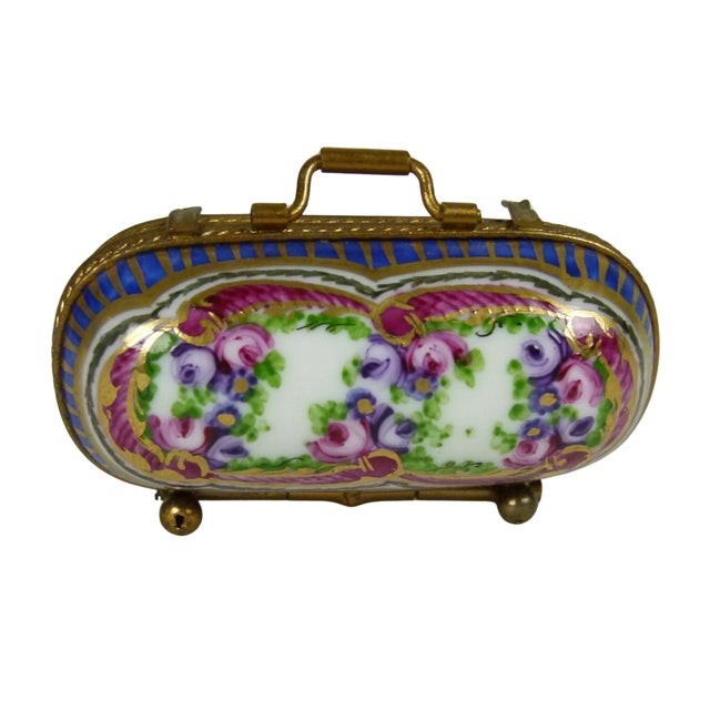 An elegant Limoges porcelain trinket box designed in the charming shape of a miniature vintage suitcase or Victorian...