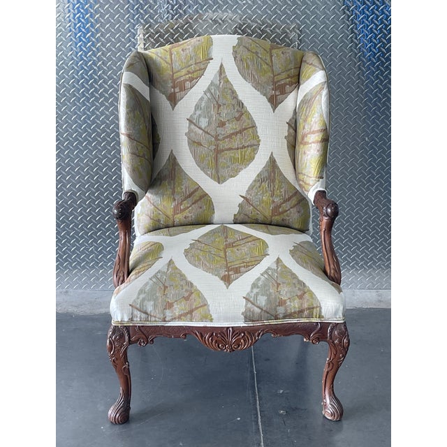 This is a traditional upholstered armchair with classic Georgian/Queen Anne–inspired detailing. The chair features a tall,...