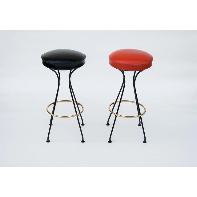 A pair of bar stools from the 50s. Stools on a metal base with a decorative brass circle. The original vinyl upholstery...