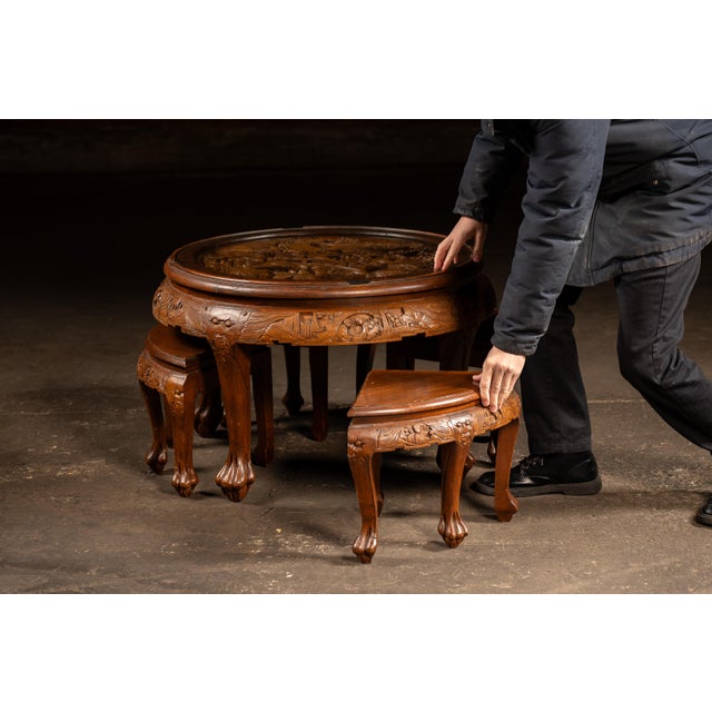 Circular carved hardwood tea table accompanied by four matching wedge-shaped stools that nest neatly beneath the tabletop....