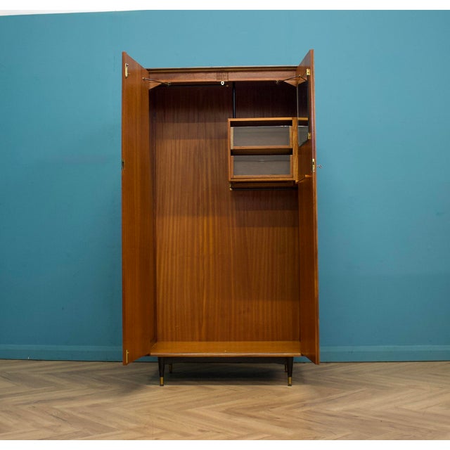 A quality mid-century wardrobe by Wrighton, made in teak veneer with a warm, well-figured grain and raised on tapered legs...