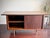 A vintage American Mid Century Modern walnut credenza featuring clean architectural lines, sliding doors, tapered legs...