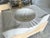 "Exquisitely hand-carved from a single block of natural white marble, this custom vanity sink features a signature fluted...