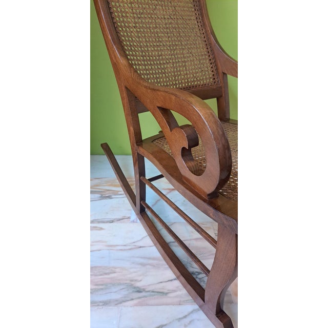 Beautiful Lincoln-style rocking chair characterized by its high, curved back, flowing arms with sinuous lines, and a...