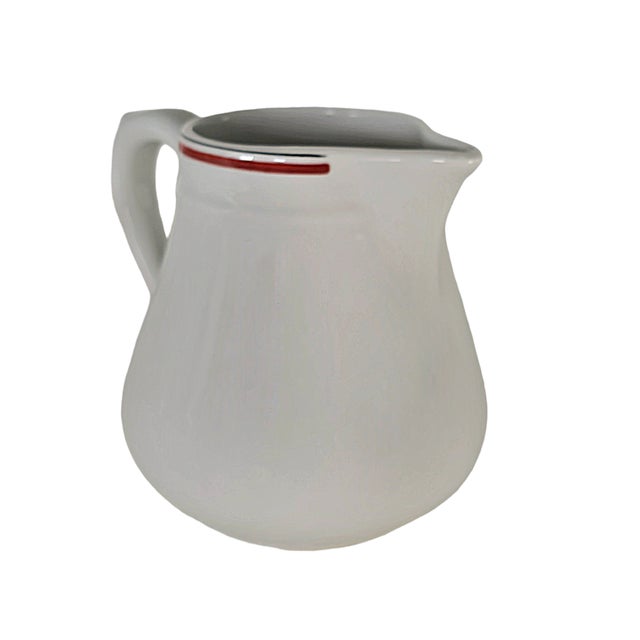 A vessel of porcelain, crisp and white, its form curved with quiet purpose. Designed for the French table, it carries the...