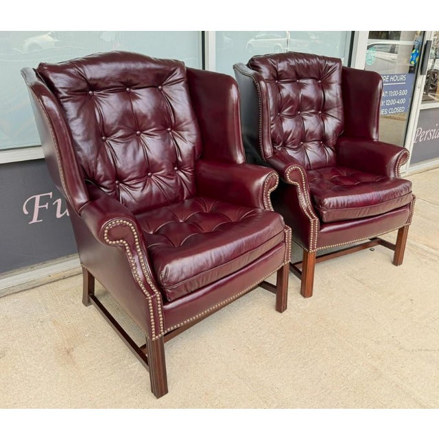 This pair of vintage wingback chairs by Classic Leather features rich maroon leather upholstery with deep button tufting,...