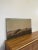 Possibly oil or acrylic on Canvas, stretched and nailed to the frame. Anonymous maker. Painting features a hillside with...