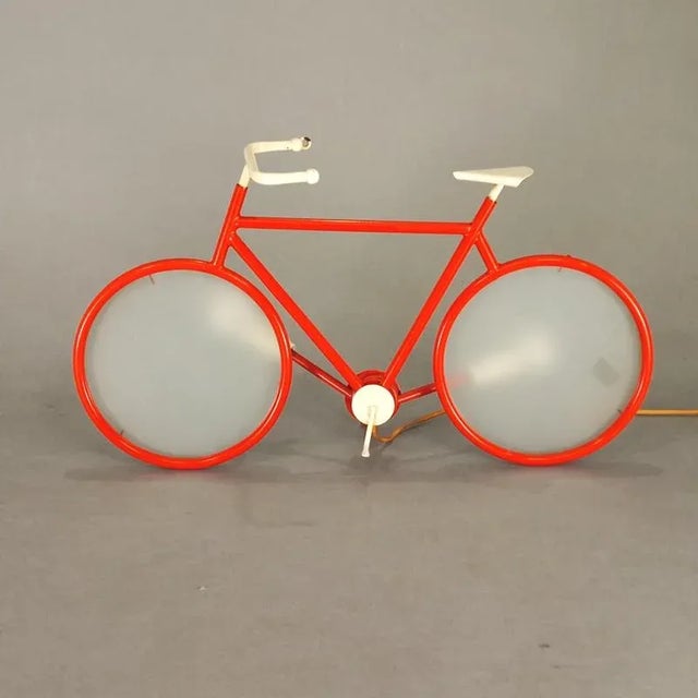 Bicycle-shaped table or wall lamp by Zicoli from the 1970s. Brick red enameled metal frame, white enameled metal...