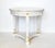 A vintage round, three-legged side table in a neoclassical style, with tapered legs, a faux marble laminate top in gray,...