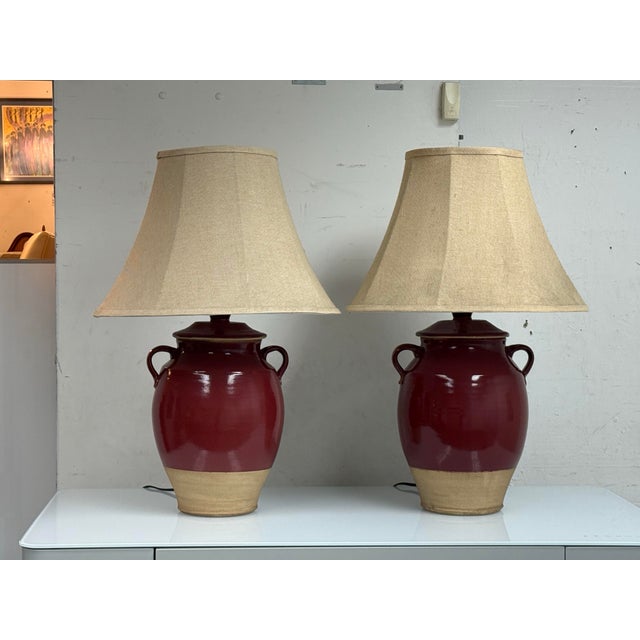 Design Plus Gallery presents a Pair of Rowe Pottery Works Table Lamps. Glazed ceramic bodies in a deep oxblood tone...